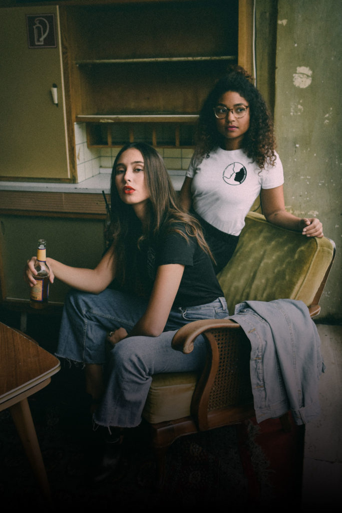 Two women sitting on a chair and posing