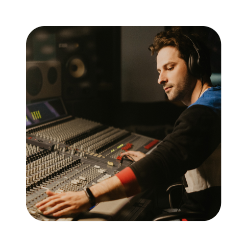 Man sitting at audio mixing board in a music studio.