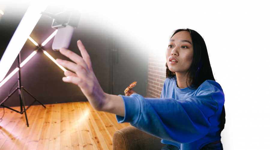 Woman filming a TikTok in front of a ring light and iPhone.